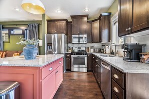 A modern kitchen with stainless steel appliances, wooden cabinets, and a marble countertop. - Gem State Getaway  Game Room+Arcades+Poker+BBQ (Boise)