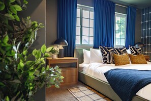 A bedroom with a bed, nightstands, a lamp, a window with curtains, and a plant. - Gem State Getaway  Game Room+Arcades+Poker+BBQ (Boise)