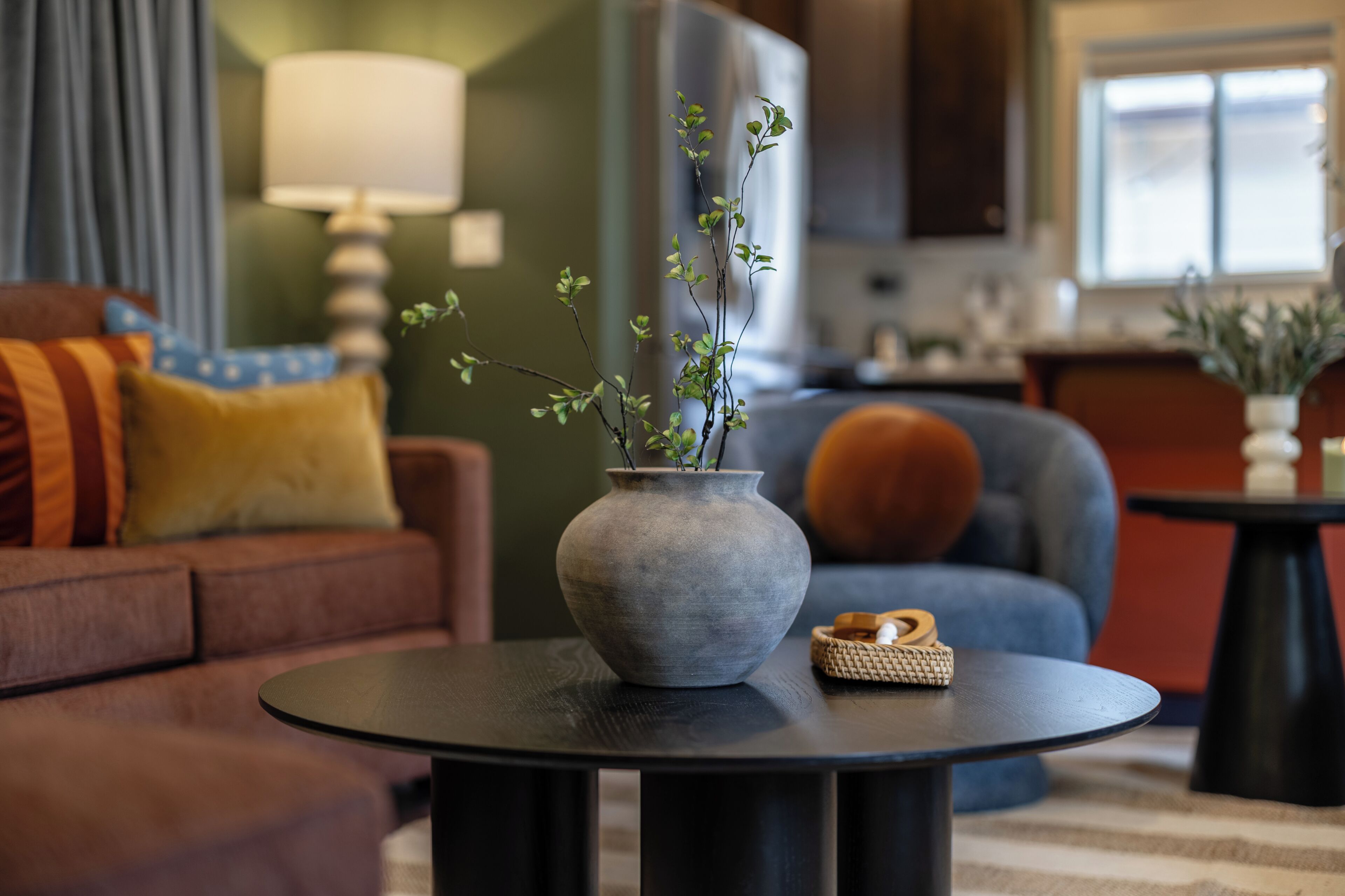 A living room with a sofa, a coffee table with a vase and a small basket, and a lamp.