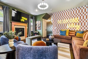 A modern living room with a fireplace, a sofa, and a neon sign. - Gem State Getaway  Game Room+Arcades+Poker+BBQ (Boise)