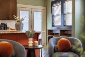 A kitchen with a coffee maker, a vase with flowers, and a dining area with chairs. - Gem State Getaway  Game Room+Arcades+Poker+BBQ (Boise)