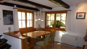 Un coin repas avec une table et des chaises en bois, un radiateur et un escalier.