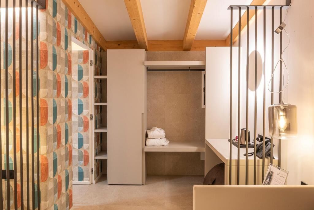 Una habitación de hotel con vestidor, escritorio con lámpara y teléfono.