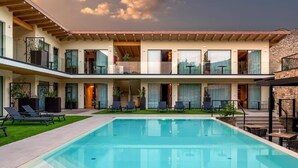 A modern hotel with a pool, multiple balconies, and a clear sky. - Relais Limonaia (Torri del Benaco)