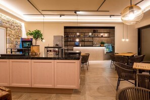 A modern kitchen with a central island, bar area with shelves of bottles, and a seating area with wicker chairs. - Relais Limonaia (Torri del Benaco)
