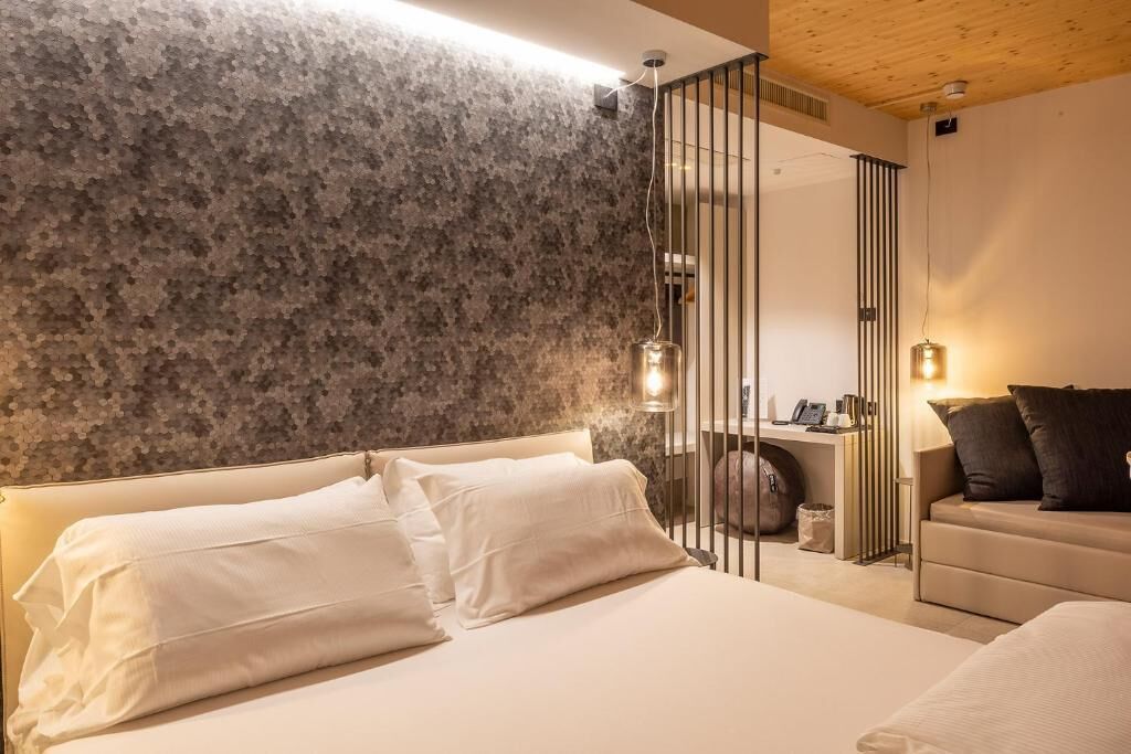 Un dormitorio con una cama grande, una mesita de noche, un espejo y una pared con textura.