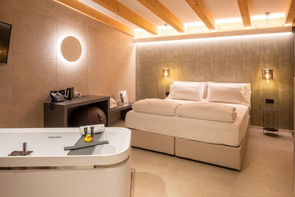 Una camera da letto moderna con un letto, un comodino e un bagno con vasca.