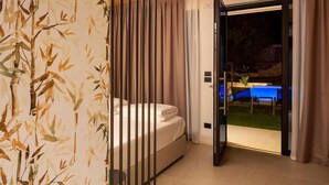 A bedroom with a bed, a sliding door leading to a balcony, and a view of a blue table and chairs outside. - Relais Limonaia (Torri del Benaco)