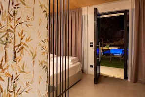 A bedroom with a bed, a sliding door leading to a balcony, and a view of a blue table and chairs outside. - Relais Limonaia (Torri del Benaco)