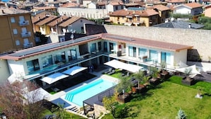 A modern villa with a swimming pool, a covered patio, and a view of the sea. - Relais Limonaia (Torri del Benaco)