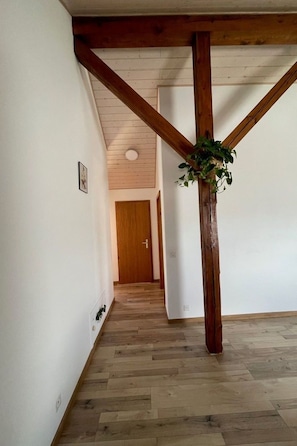 Ein Flur mit Holzbalken, einer Holztür und einem Blumentopf.