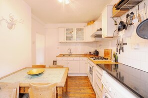 A kitchen with white cabinets, a wooden table, and a stove. - Stylish 1-Bed in Bethnal Green • Calm & Central - Pass the Keys (London)