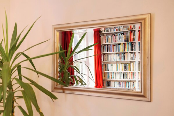Ein Zimmer mit Fenster, einer Bücherwand und einem Blumentopf.