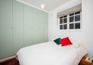 Une chambre à coucher avec un lit, une fenêtre et une armoire.