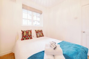 Ein Schlafzimmer mit einem Bett, zwei Kissen, einem Fenster und einer Tür.