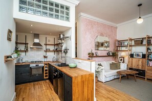 Una cocina moderna con una isla central, una zona de comedor con un sofá blanco y una sala de estar con una mesa de centro de madera.