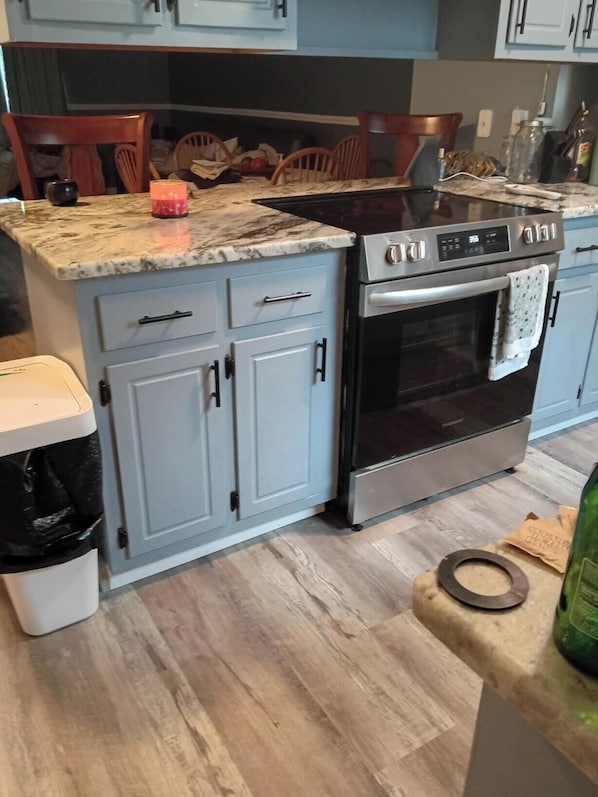 Eine Küche mit hellblauen Schränken, einem Edelstahlbackofen und einer Marmorarbeitsplatte.