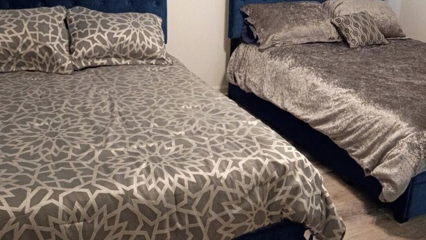 A room with two beds, each with a headboard and pillows.
