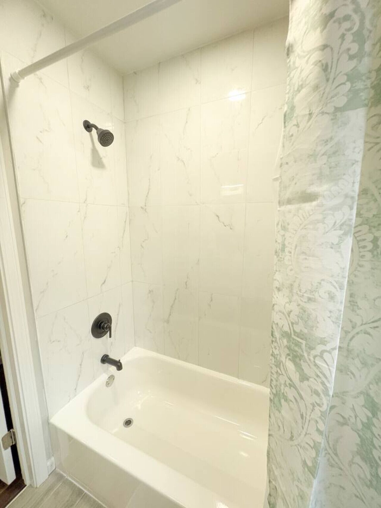 Een badkamer met een bad, een douchekop en een toilet.