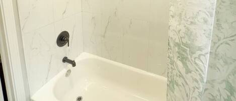 Een badkamer met een bad, een douchekop en een toilet.