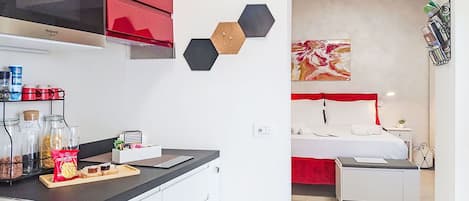 Una cocina moderna con armarios rojos, encimera negra y diversos alimentos.