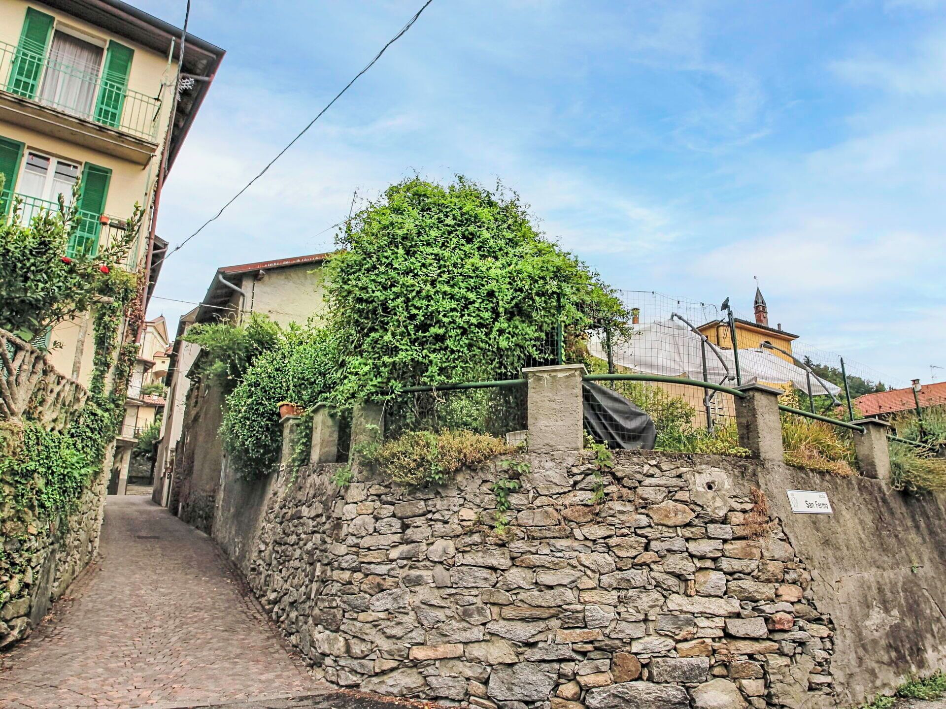 Un étroit sentier de pierre mène à un mur de pierre sur lequel est apposée une plaque portant l’inscription « San Fermino ».