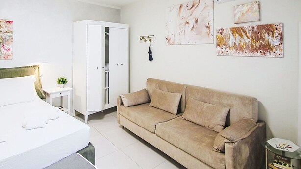A modern bedroom with a bed, a white wardrobe, a beige sofa, and a small bedside table. - Beautiful apartment for 3 guests with WIFI, A/C, TV and balcony (Colazza)