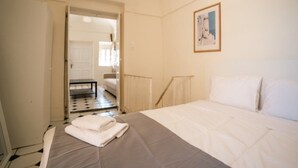 A bedroom with a bed, a door leading to another room, and a framed picture on the wall.