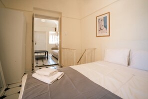 A bedroom with a bed, a door leading to another room, and a framed picture on the wall.