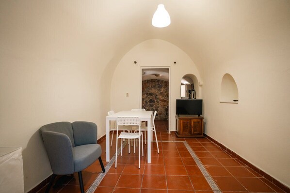 A compact living space with a dining area, a seating area, and a television.
