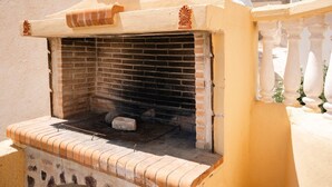 A brick-built outdoor grill with a white railing in the background.