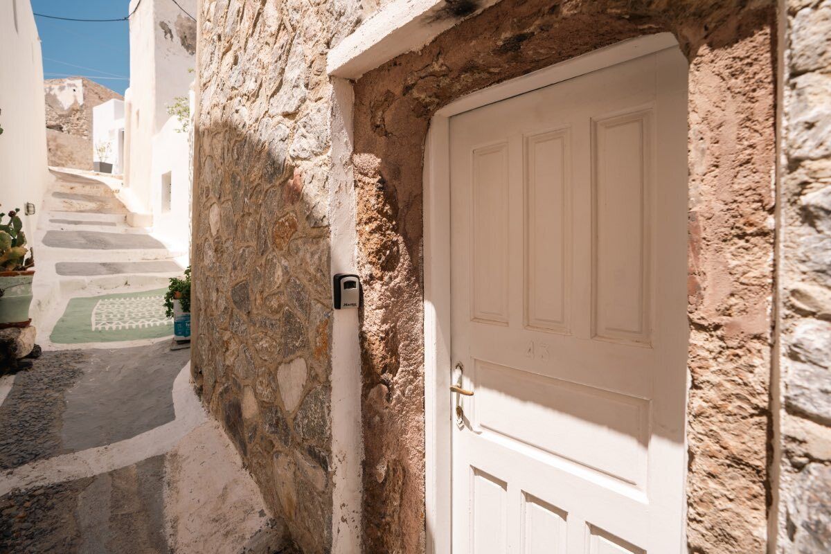 A narrow street with a white door and stone walls.