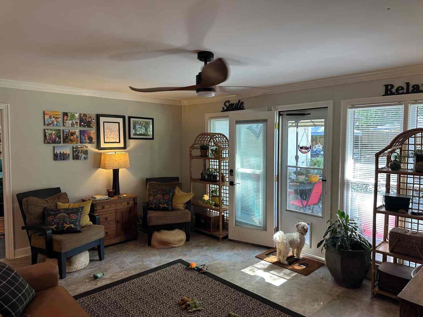 Un salon confortable avec un ventilateur de plafond, un chien et une porte sur laquelle est écrit « Détendez-vous ».