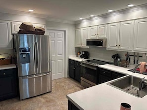 A modern kitchen with stainless steel appliances, white cabinetry, and a built-in oven. - UGA GAME DAY Home w/3 bedrooms-6 People (Athens)