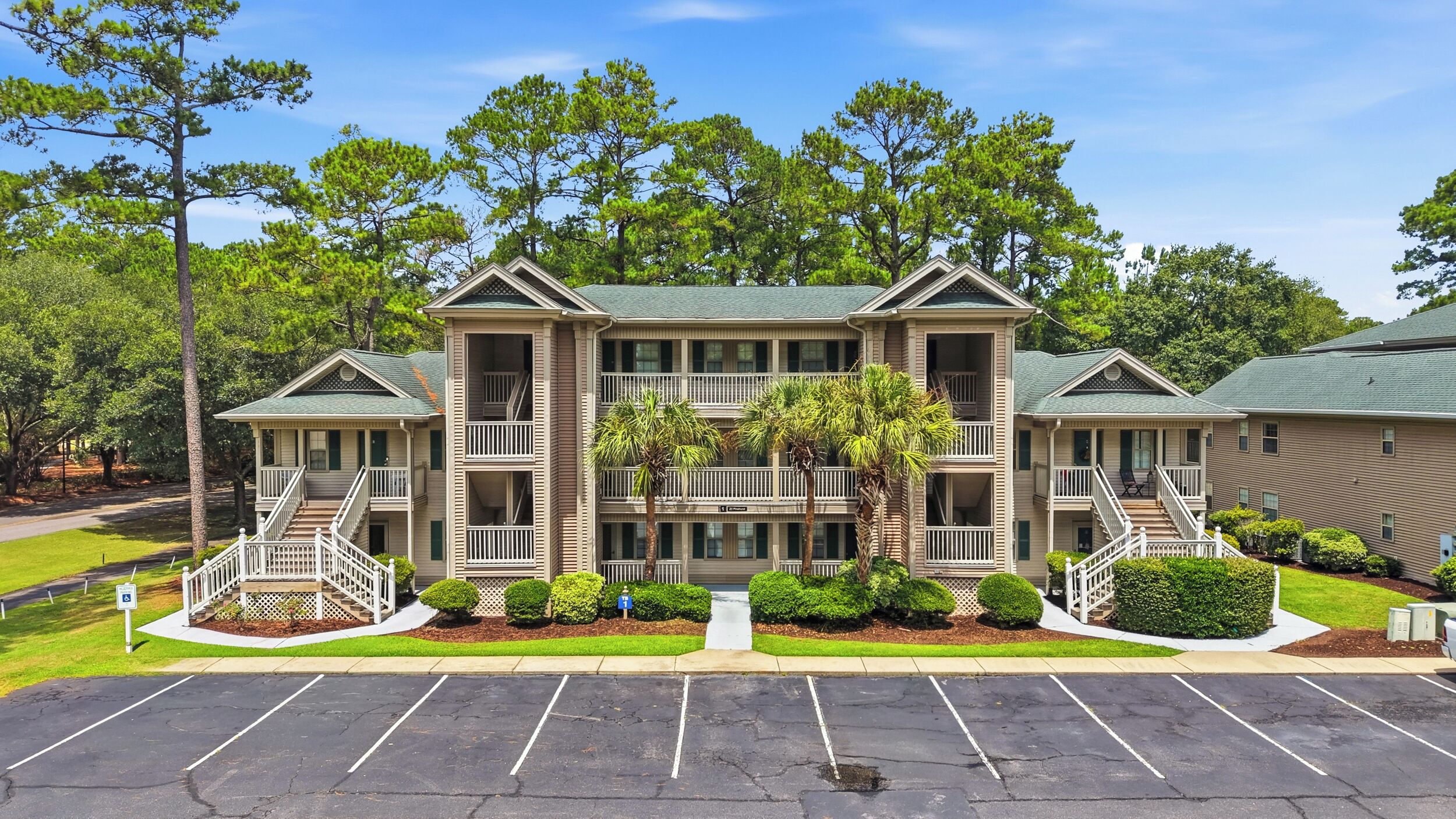 A multi-story hotel with a central courtyard, balconies, and a parking lot.