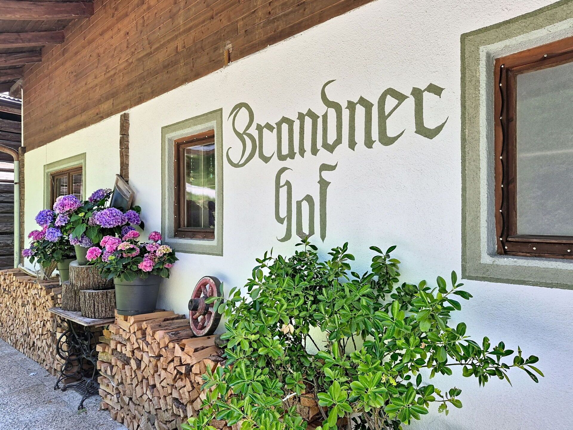 Un bâtiment sur lequel est peint le nom « Brandnegg », avec des poutres en bois au-dessus et des plantes en pot à l’extérieur.