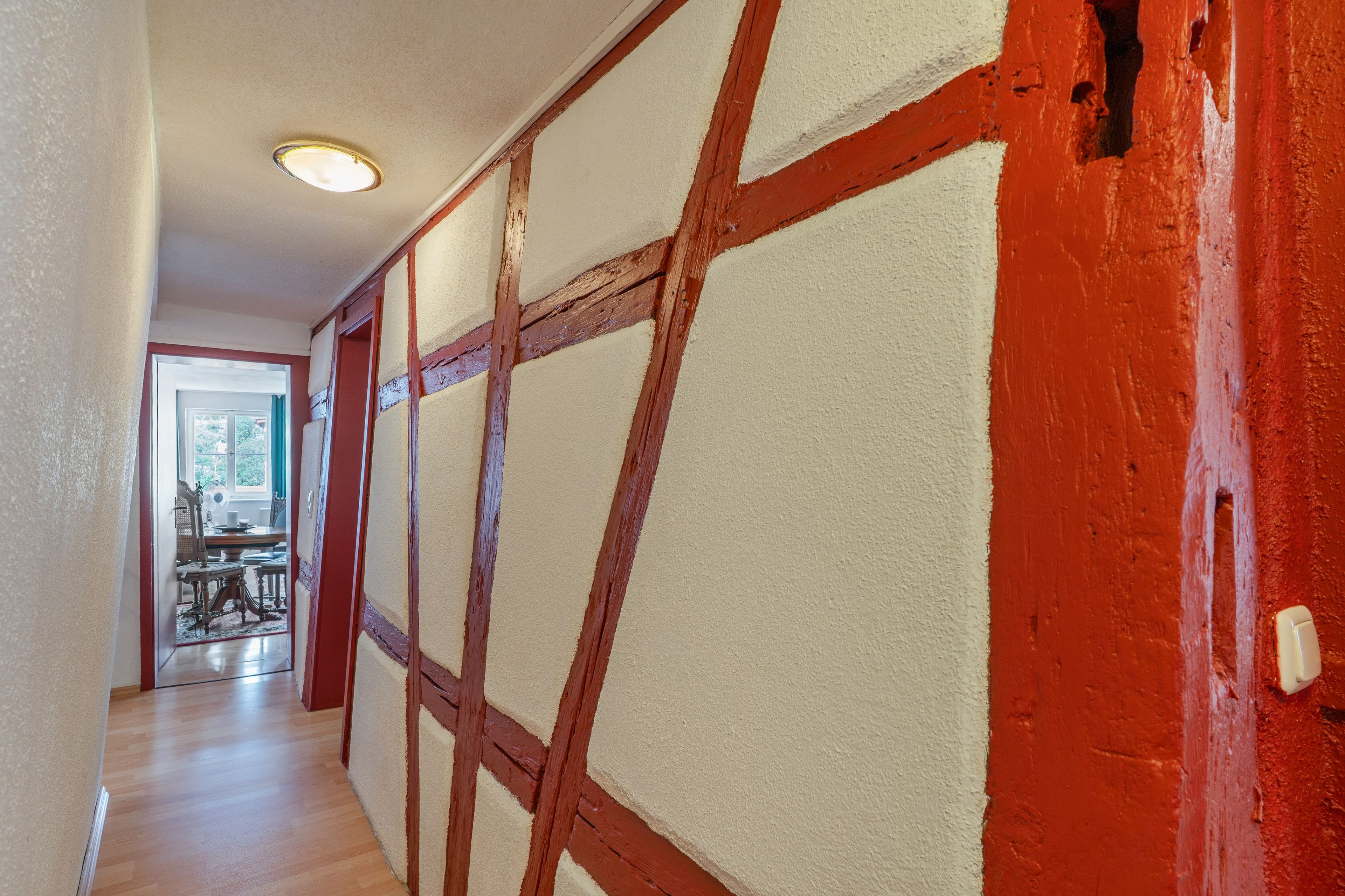 A hallway with exposed wooden beams and a red wall.