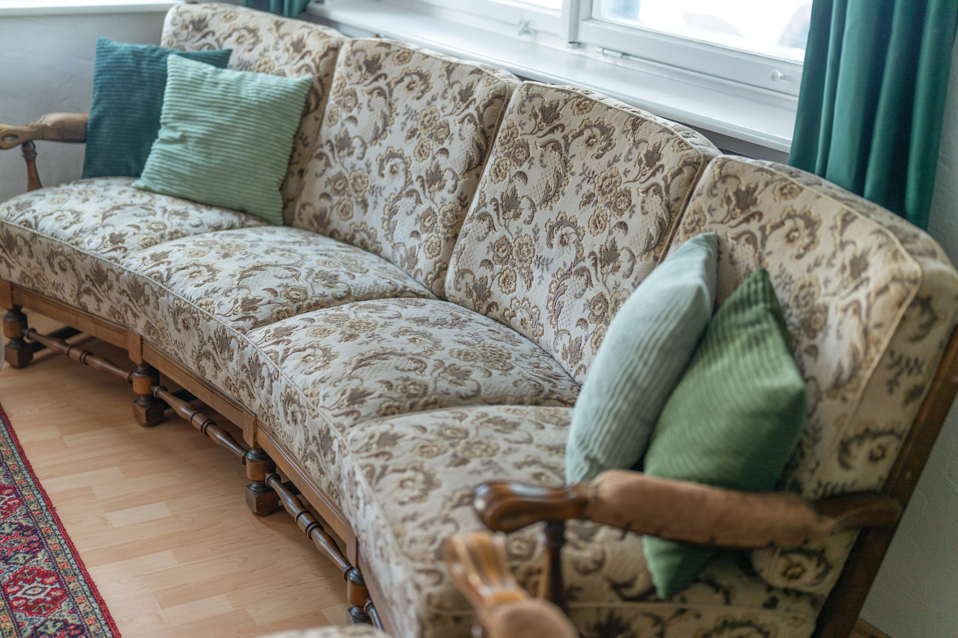 Ein Sofa mit Stoffbezug, Holzrahmen und zwei Kissen.