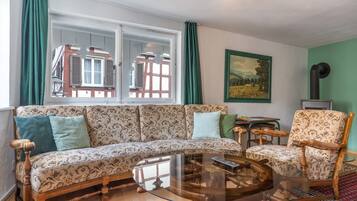 A living room with a sofa, armchair, coffee table, and a painting on the wall.