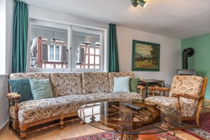 Ein Wohnzimmer mit Sofa, Sessel, Couchtisch und einem Gemälde an der Wand.