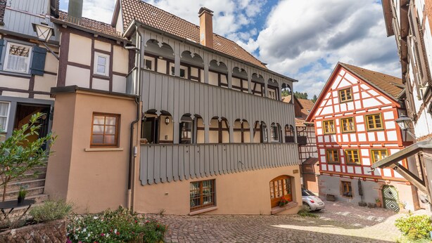 Une cour intérieure européenne traditionnelle, avec des allées pavées, une voiture garée au centre et des bâtiments aux façades à colombages.