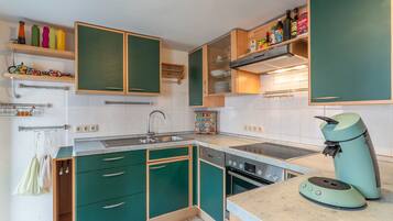 A kitchen with green cabinets, a built-in oven, a sink, and a coffee maker.