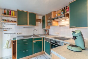 Eine Küche mit grünen Schränken, einem Backofen, einer Spüle und einer Kaffeemaschine.