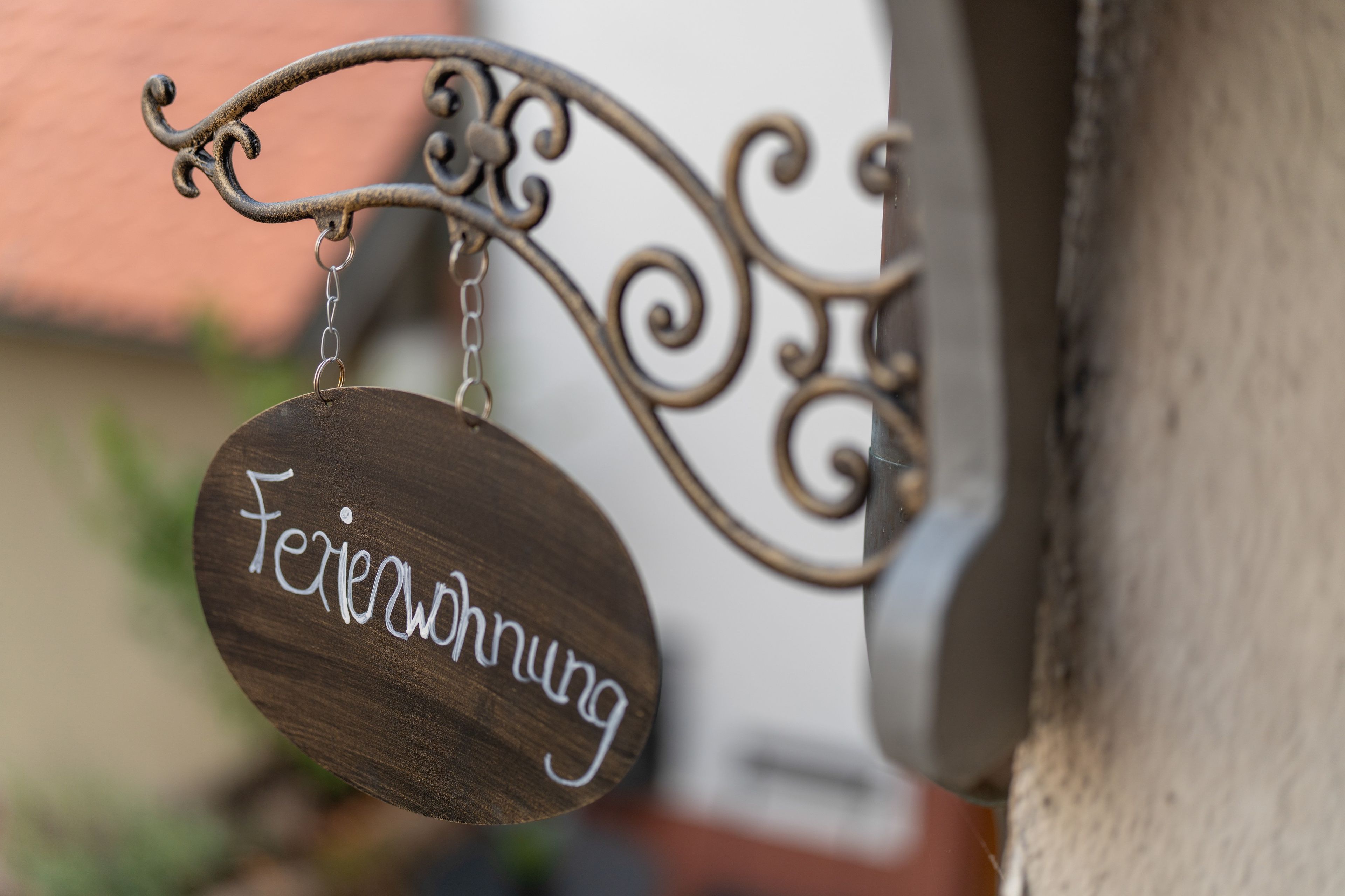 A wooden sign with the text 'Feriewohnung' hanging from a metal fixture.