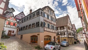 Une rue typique d'Europe, avec ses pavés, ses bâtiments historiques à colombages et ses voitures garées.