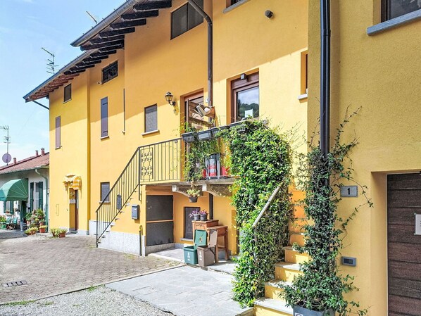 Un edifici groc amb una escala que condueix a un balcó, una porta i una finestra.