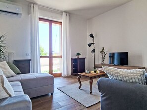 Ein Wohnzimmer mit Sofa, Sessel, Couchtisch und Fernseher.