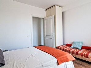 Ein Schlafzimmer mit einem Bett, einem Kleiderschrank und einer Bank mit Kissen.