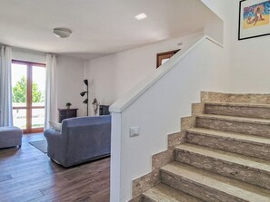 Ein Wohnzimmer mit einer Couch, einer Lampe und einer Treppe, die zu einer oberen Etage führt.