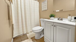 Un baño con inodoro, cortina de ducha, lavabo y espejo.